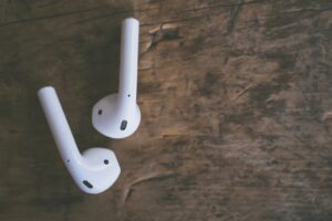 Close-up of white wireless earbuds on a rustic wooden surface, highlighting modern audio technology.