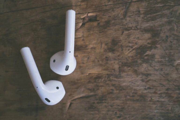 Close-up of white wireless earbuds on a rustic wooden surface, highlighting modern audio technology.