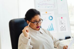 Focused woman reviewing financial graphs during a presentation in a modern office setting.