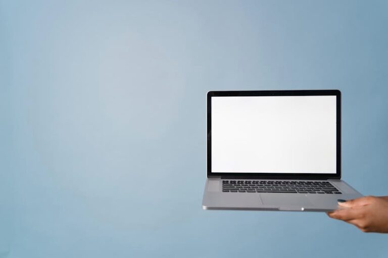 A person holding a laptop with a blank screen against a blue background, perfect for mockups.