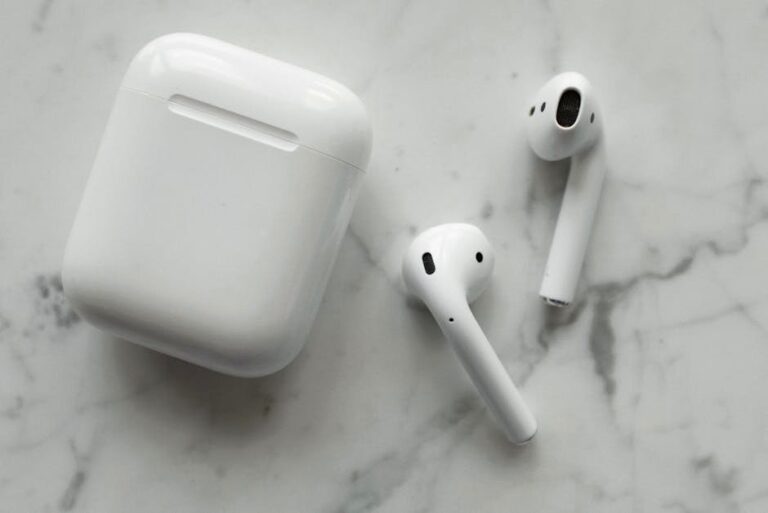 A close-up view of white wireless earbuds and their case on a marble surface.