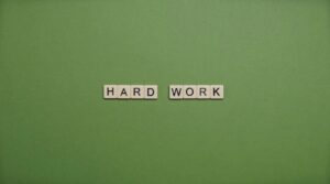 Tiles spelling 'hard work' on a green background symbolizing diligence and effort.