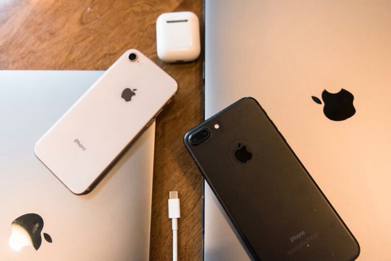 A collection of Apple products including iPhones, MacBooks and AirPods displayed on a wooden table.