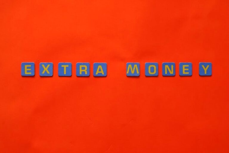 Bright orange background with 'EXTRA MONEY' spelled in blue and yellow tiles, illustrating financial concepts.