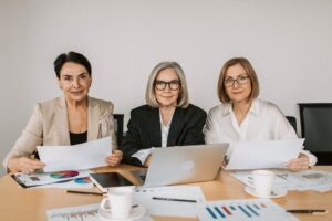 Three senior women discussing business strategies at a modern office table.