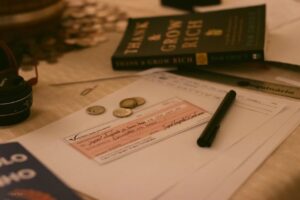 Close-up of a business desk with a check, coins, pen, and financial books, creating a financial planning vibe.