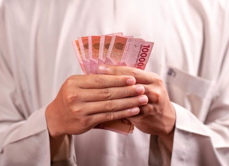 Close-up of hands holding 100,000 Indonesian Rupiah notes, symbolizing wealth and finance.