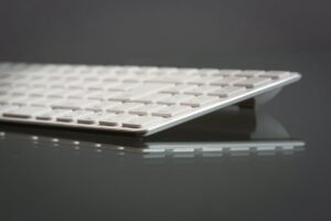 Stylish close-up of a modern slim keyboard on a reflective surface, showcasing minimalist tech design.