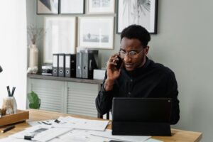 Professional man working at his desk on a call, managing documents and using a tablet.