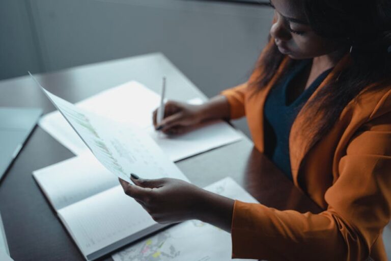 Professional woman in office attire reading documents at her desk, showcasing leadership and focus.