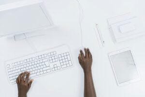 Top view of a minimalist workspace with a computer, keyboard, and tablet.