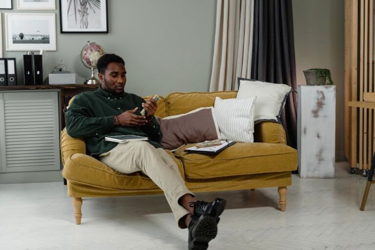 African American businessman sitting on a couch, managing finances with cash and documents.