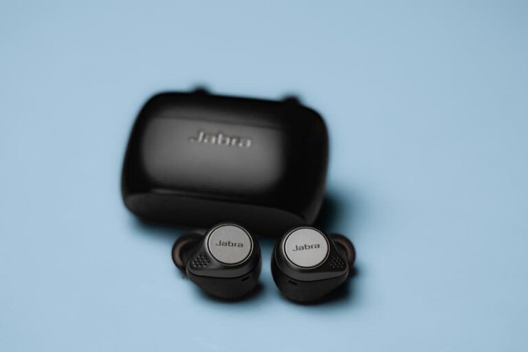 Close-up of Jabra wireless earphones with charging case on a blue background, ideal for tech and lifestyle themes.