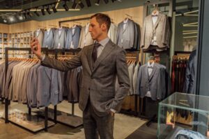 Man in suit shopping and taking selfie in upscale fashion boutique.