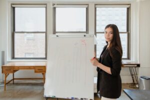 Confident businesswoman presenting a bar chart in a modern office setting.