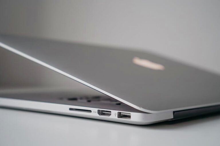 Close-up view of a sleek silver laptop with partially open lid, highlighting ports and sleek design.