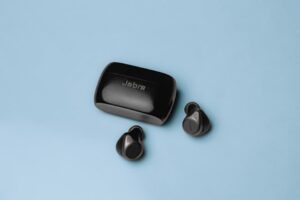 Wireless Jabra earbuds with charging case on a minimalist blue background, ideal for technology enthusiasts.