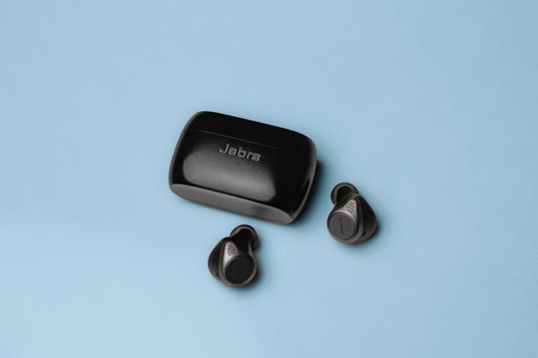 Wireless Jabra earbuds with charging case on a minimalist blue background, ideal for technology enthusiasts.