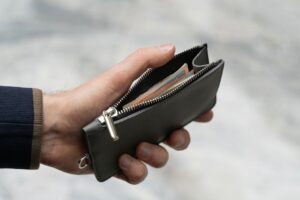 Hand holding a leather wallet with visible cash, emphasizing finance and savings.