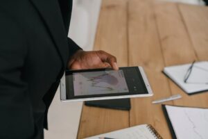 Businessperson reviewing data charts on a tablet device in an office setting.