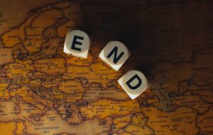 Close-up of dice spelling 'END' placed on a map of Europe, symbolizing finish line or travel completion.