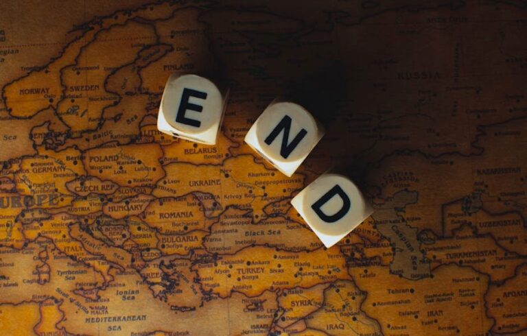 Close-up of dice spelling 'END' placed on a map of Europe, symbolizing finish line or travel completion.
