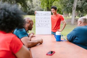 A diverse group of adults engaged in a motivational team building session outdoors.