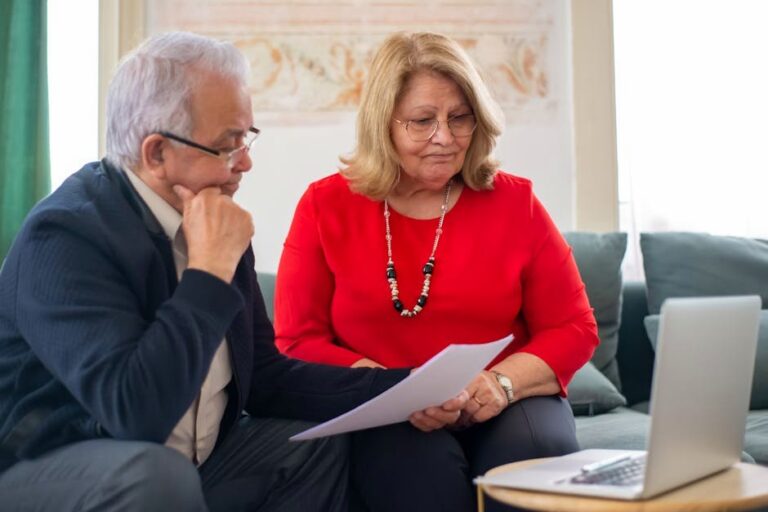 Elderly couple reviewing financial documents together at home in Portugal.