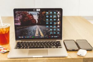 A clean desk with a laptop, two smartphones, and iced tea, creating a modern workspace environment.