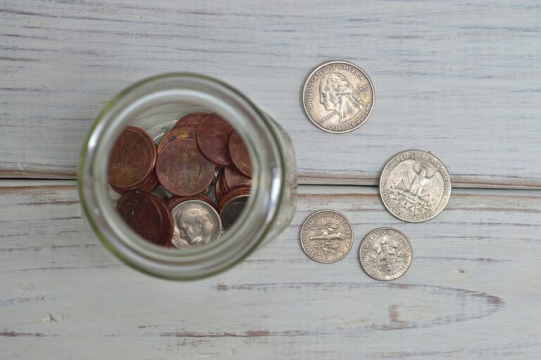 Top view of a jar filled with coins placed on a wooden table, depicting savings.