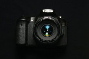 High-quality DSLR camera with zoom lens on a sleek black background. Ideal for photography concepts.