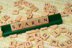 Close-up of Scrabble tiles spelling 'Sparen' on a green tile holder.