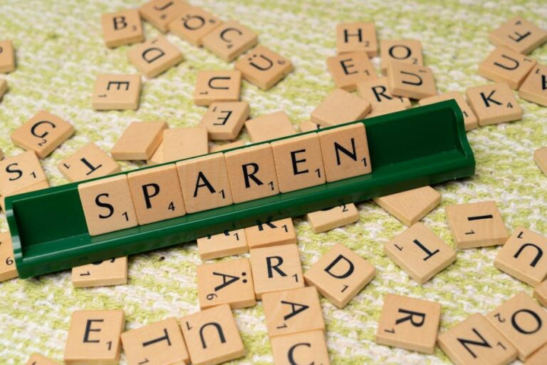Close-up of Scrabble tiles spelling 'Sparen' on a green tile holder.