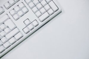 A minimalist white keyboard in a flat lay on a white background, ideal for tech-related content.