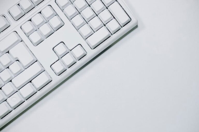 A minimalist white keyboard in a flat lay on a white background, ideal for tech-related content.