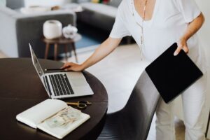A woman multitasking with a laptop and tablet in a modern office setting.
