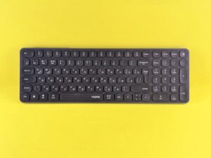 A sleek black wireless keyboard displayed against a vibrant yellow background, perfect for tech themes.