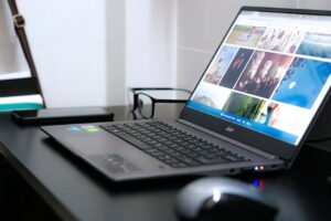 A sleek laptop on a desk with glasses and mouse, ideal for tech or business themes.