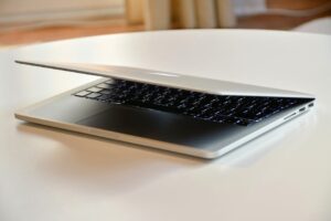 A modern MacBook laptop with a sleek design, slightly closed on a white table indoors.