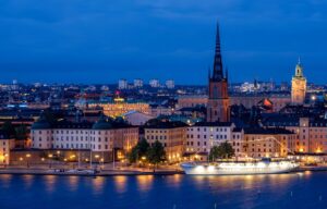 city cityscape waterfront illuminated ship architecture skyline historic center church steeple water sea night evening twilight lights mirroring stockholm sweden nature scandinavia