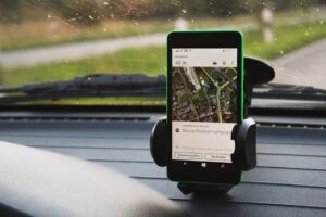 Smartphone with GPS navigation mounted on car dashboard, daylight view.