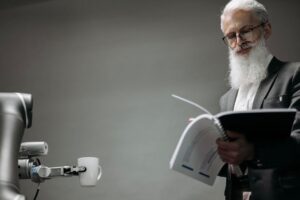 Elderly man reads as a robotic arm holds a coffee cup, showcasing technology integration.