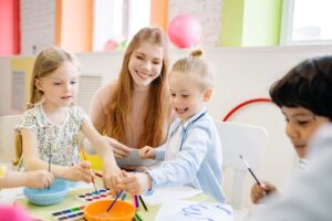 Young children enjoy painting with a teacher in a vibrant classroom setting.