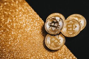 Gold Bitcoin coins displayed on a sparkling gold texture, representing digital currency and finance.