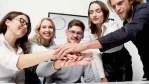 A diverse group of colleagues stacking hands in a gesture of teamwork and unity in an office setting.