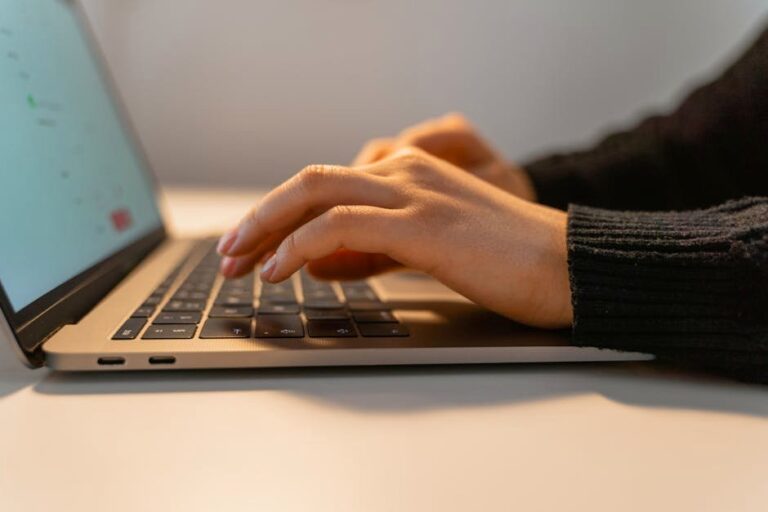 Close-up view of hands typing on a laptop keyboard, illustrating the concept of remote work and technology.