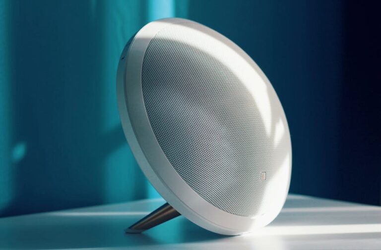 Close-up of a modern wireless speaker with a minimalist design, lit by natural light indoors. Ideal for tech product showcase.