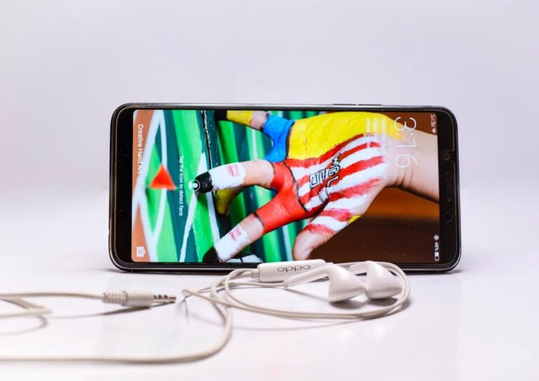 Smartphone displayed with wired earphones, featuring colorful screen on a white background.