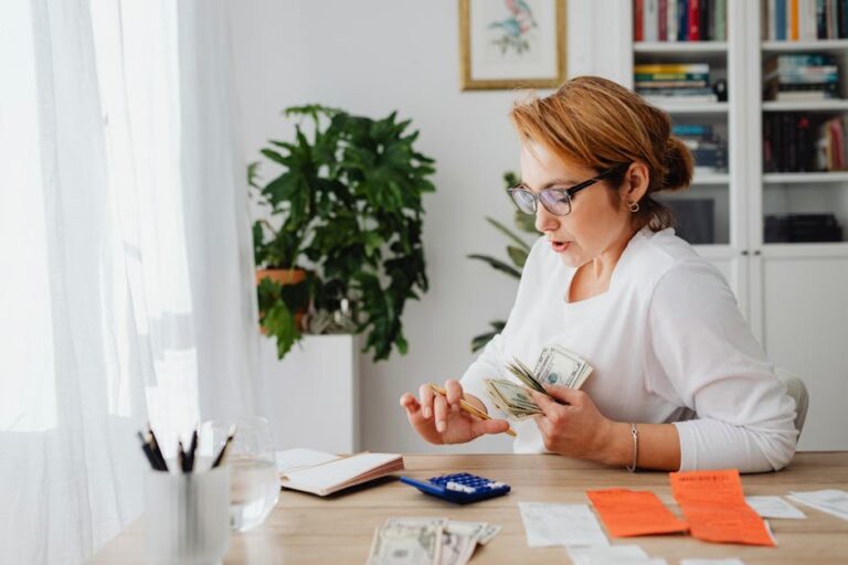 A woman sitting at her desk, counting money for home budgeting management.