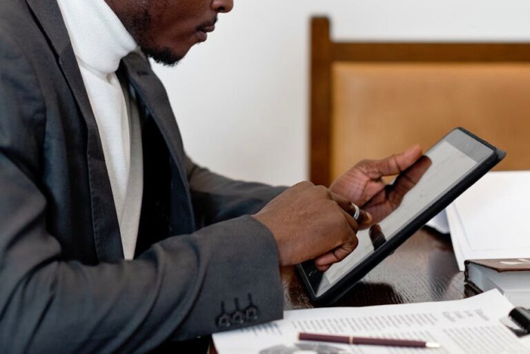 A businessman in a suit uses a tablet at a desk, focusing on technology for productivity.